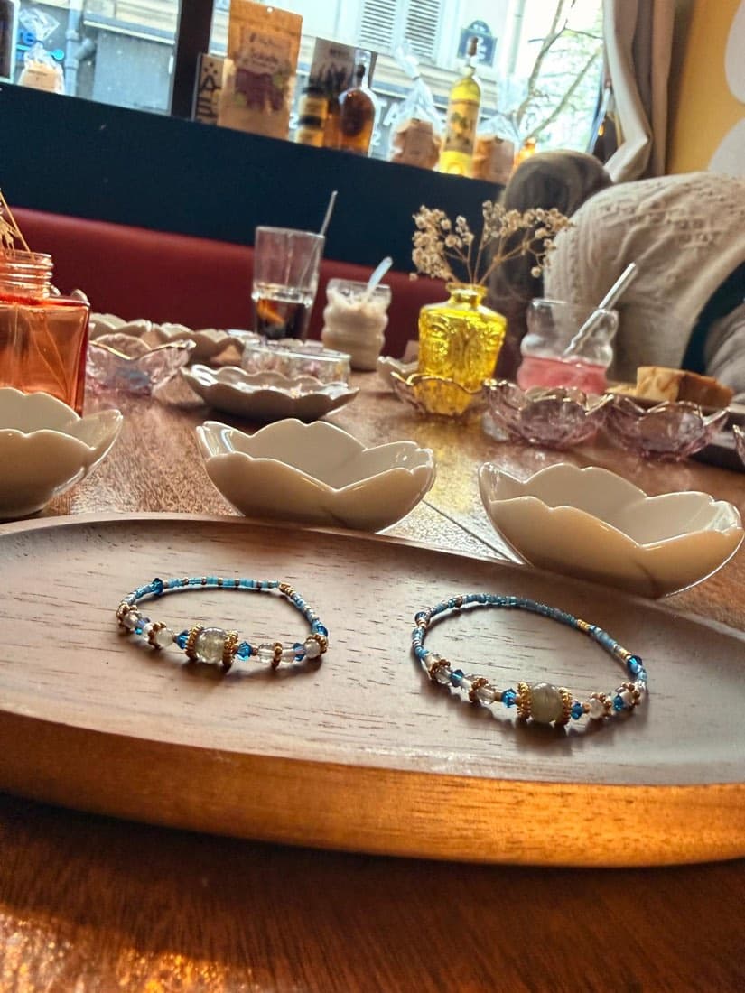 Deux bracelets en pierres fines et perles créés pendant l’atelier Maison Exquiz chez Ty Louis, posés sur un plateau en bois