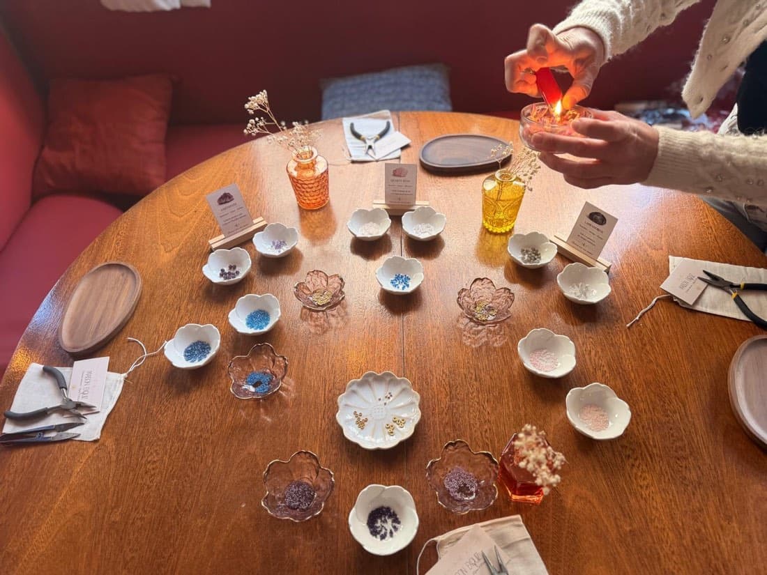 Les pierres et perles de Maison Exquiz disposées dans des coupelles sur une table de Ty Louis, prêtes pour l’atelier création de bracelet