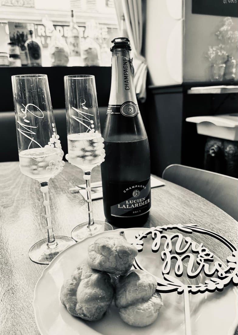 Deux flûtes « Mr & Mrs », une bouteille de champagne et des choux de la pièce montée, sur une table de mariage chez Ty Louis