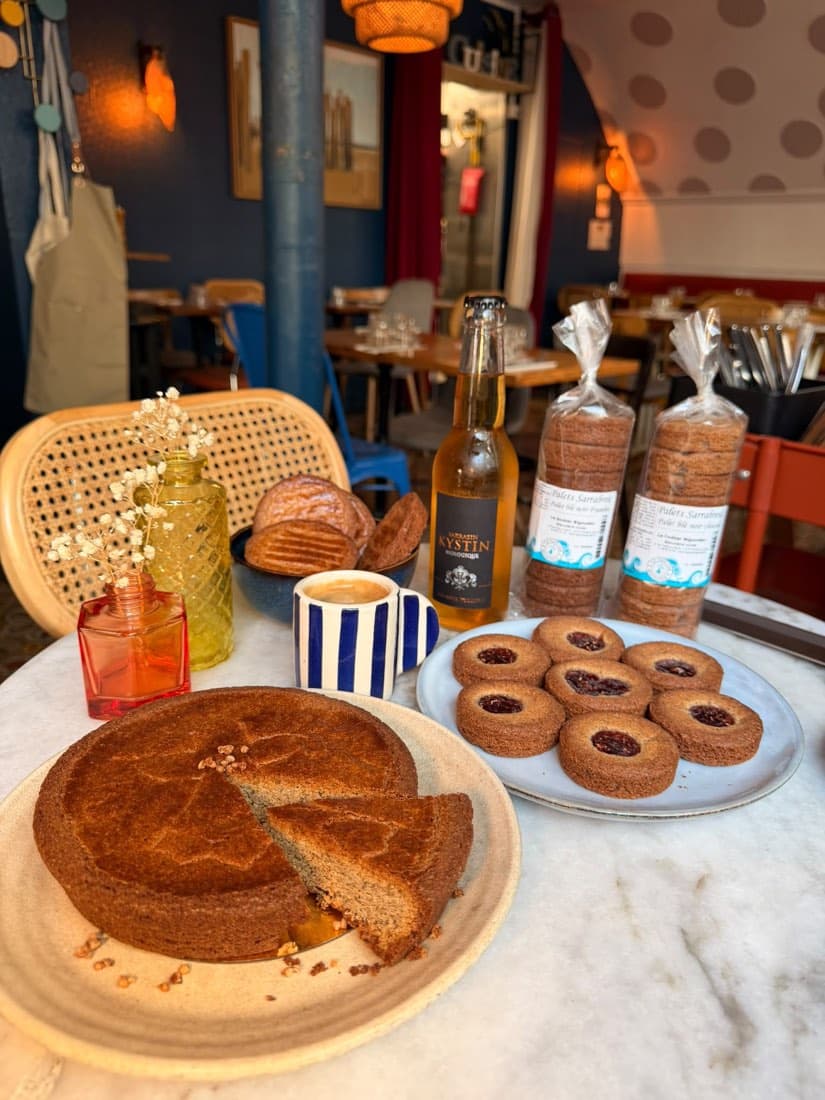 Gâteau breton au blé noir entamé, palets à la framboise et sachets de palets Sarrabreizh du Goûter Bigouden sur une table de Ty Louis
