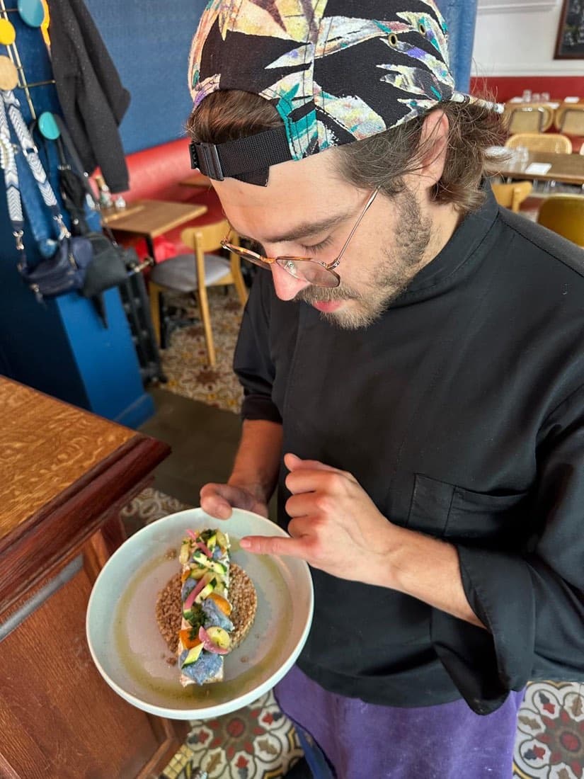 Un cuisinier de la brigade de Ty Louis dresse une assiette de poisson et de sarrasin