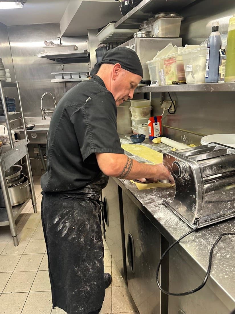 Un cuisinier de Ty Louis passe une pâte fraîche au laminoir dans la cuisine du restaurant