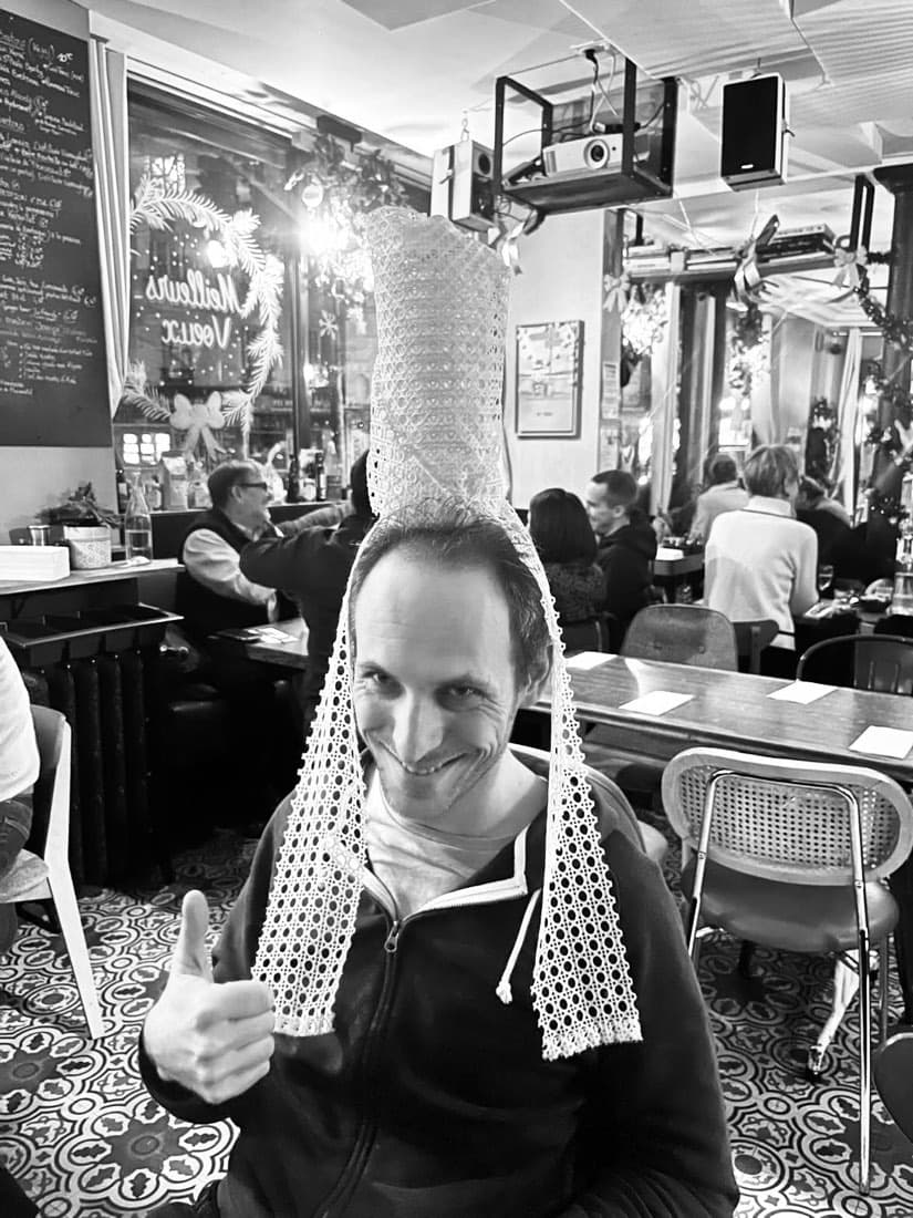 Un client de Ty Louis fait un pouce levé, coiffé de la coiffe bigoudène, dans la salle décorée pour les fêtes