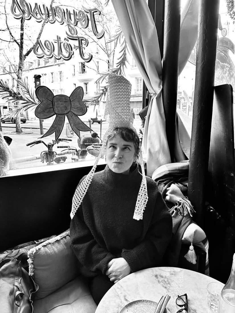 Ambiance de la galette des rois chez Ty Louis : une convive coiffée de la bigoudène devant la vitrine « Joyeuses Fêtes »