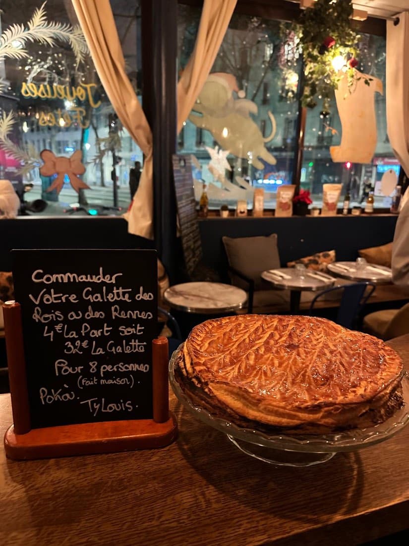 Une galette des rois dorée faite maison sur un présentoir, à côté de l’ardoise de commande de Ty Louis, restaurant breton à Paris 12