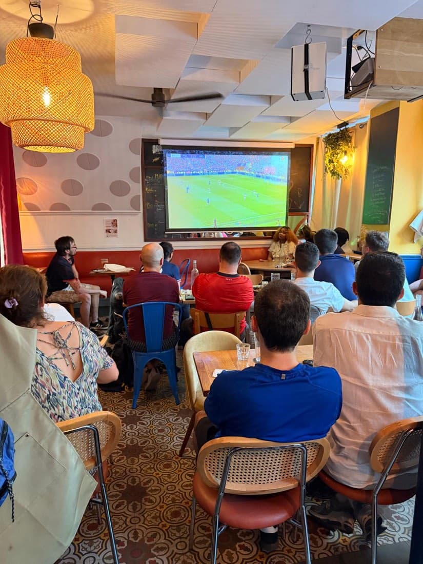 Des clients de Ty Louis regardent un match de football sur grand écran dans la salle du restaurant, à Paris 12