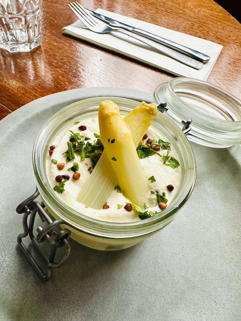 Asperges blanches servies dans un bocal avec une crème et des noisettes concassées, chez Ty Louis