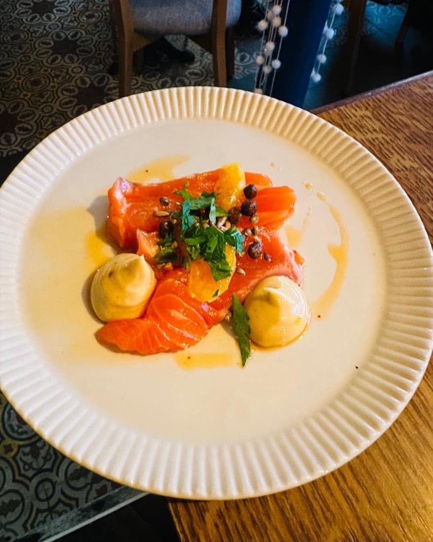 Gravlax de saumon mariné avec quenelles de crème, suprêmes d’agrume et noisettes, chez Ty Louis