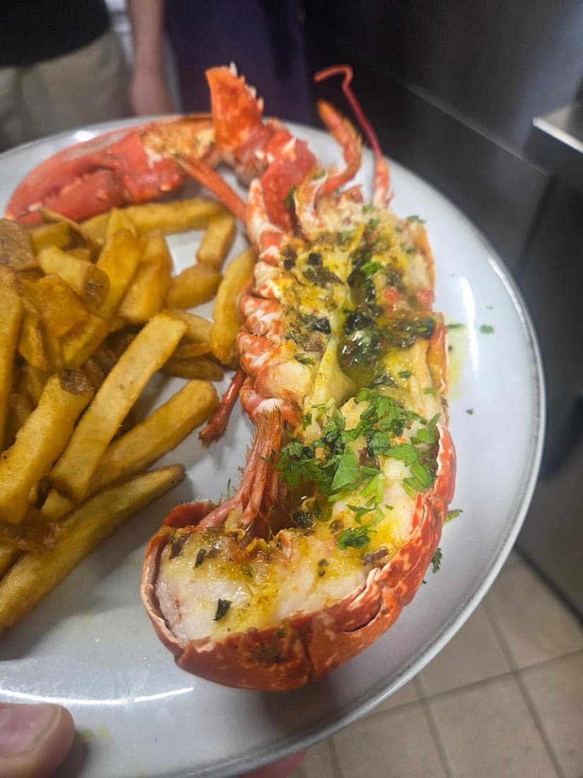 Demi-homard breton grillé au beurre persillé, accompagné de frites, servi chez Ty Louis à Paris 12