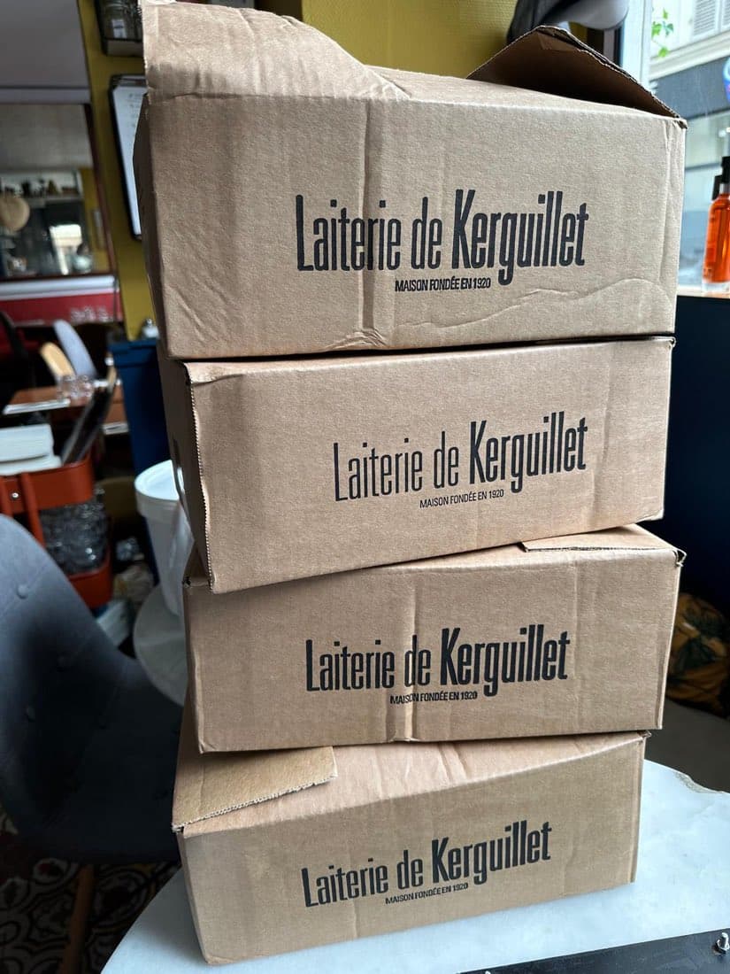 Cartons « Laiterie de Kerguillet, maison fondée en 1920 » empilés après la visite