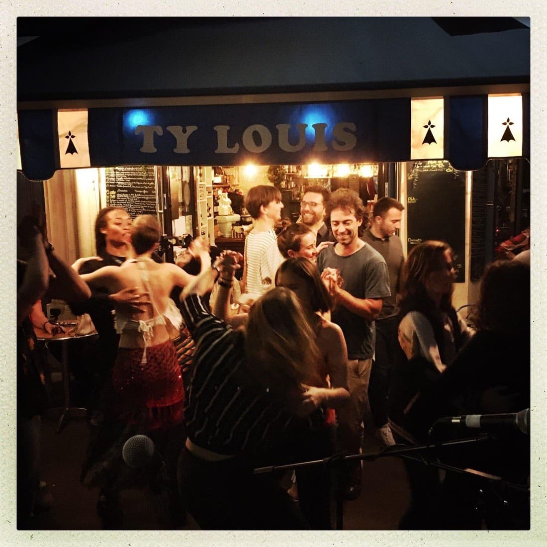 Une soirée festive de nuit chez Ty Louis : des clients dansent au son d’un groupe live sous l’enseigne du restaurant