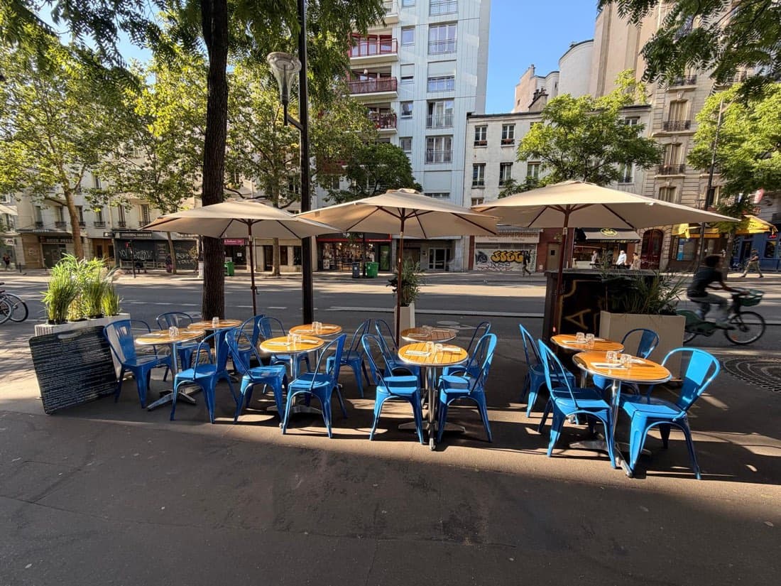 La terrasse de Ty Louis avec ses parasols et ses chaises bleues, sur le large trottoir du Faubourg Saint-Antoine