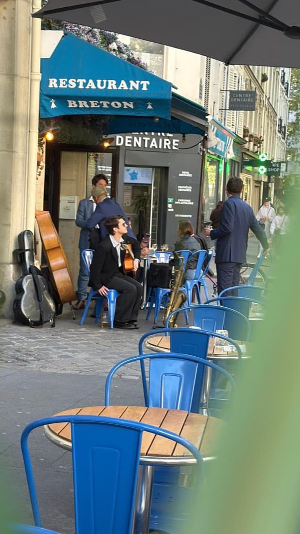 Un trio de musiciens — guitare, contrebasse et saxophone — joue devant le « Restaurant breton » Ty Louis à Paris 12
